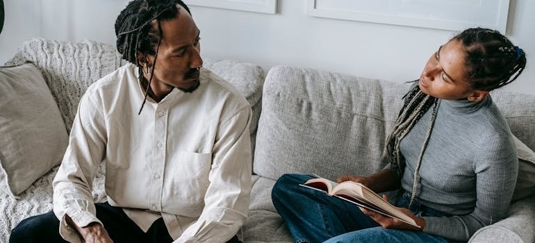 Couple sitting on the couch and having a serious conversation.