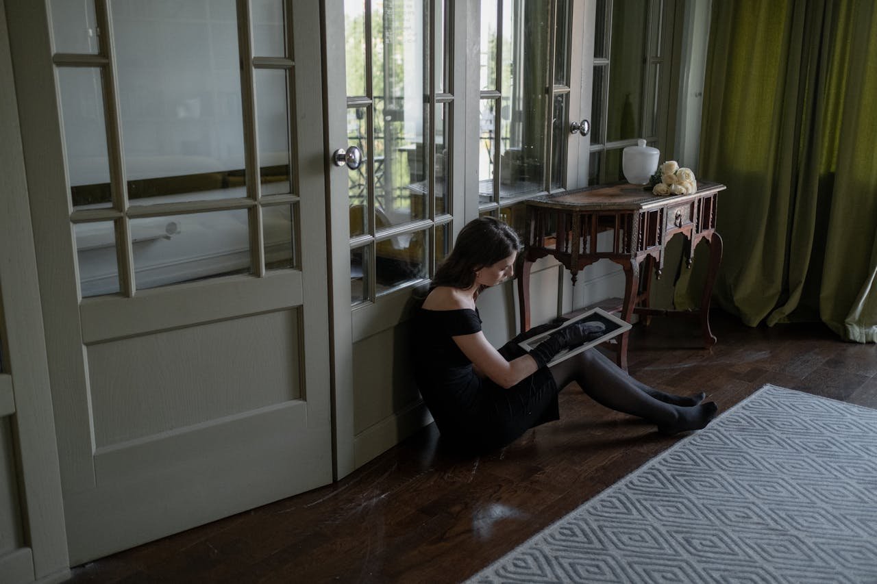 Woman sitting on the floor, looking at a picture while coping with loss.