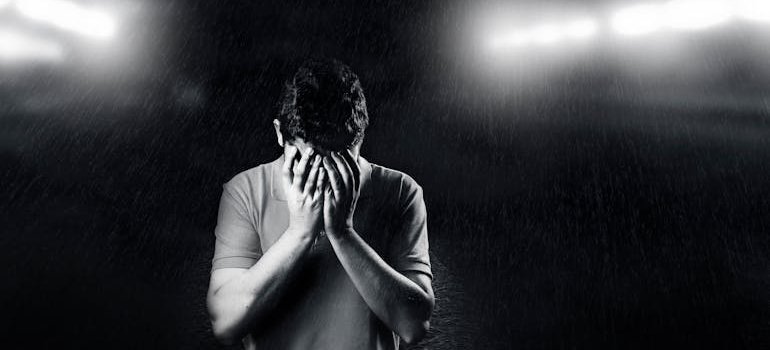 Scared man covering his face while struggling with LSD and bipolar disorder.