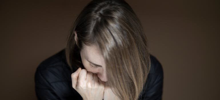 Woman putting her head on her hands while feeling the shame of addiction.