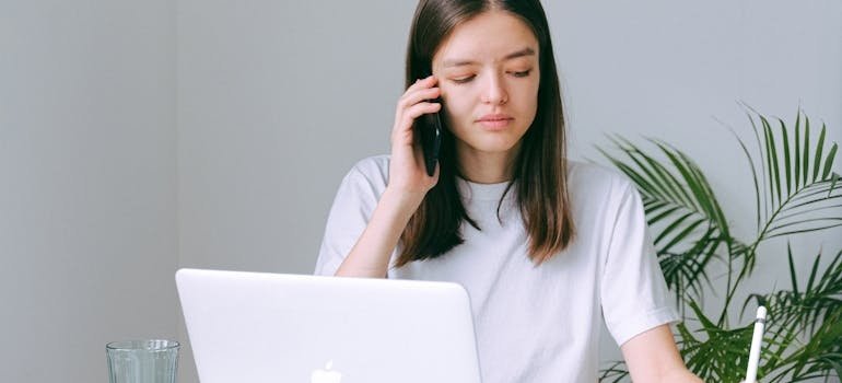 Woman making a phone call while writing in a notebook.