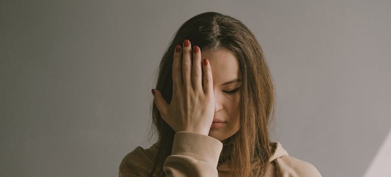 Woman sitting on a chair covering her face while worrying about how long does cannabis-induced anxiety last.