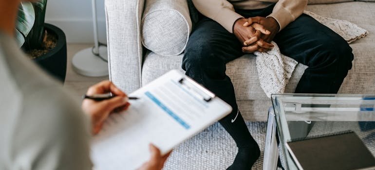 Therapist writing in a clipboard while talking with a patient about how to develop self-esteem.