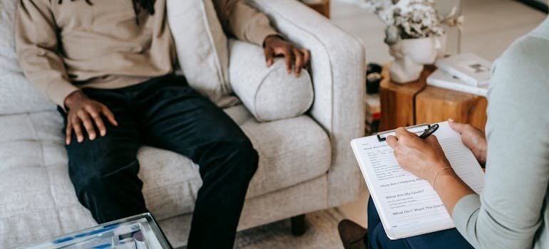 Therapist writing in a clipboard while talking to a patient about holiday suicide awareness.