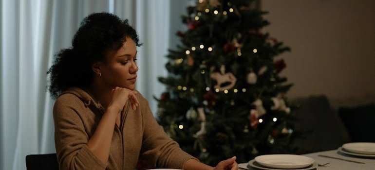Sad woman sitting at a dinner table looking at her plate.