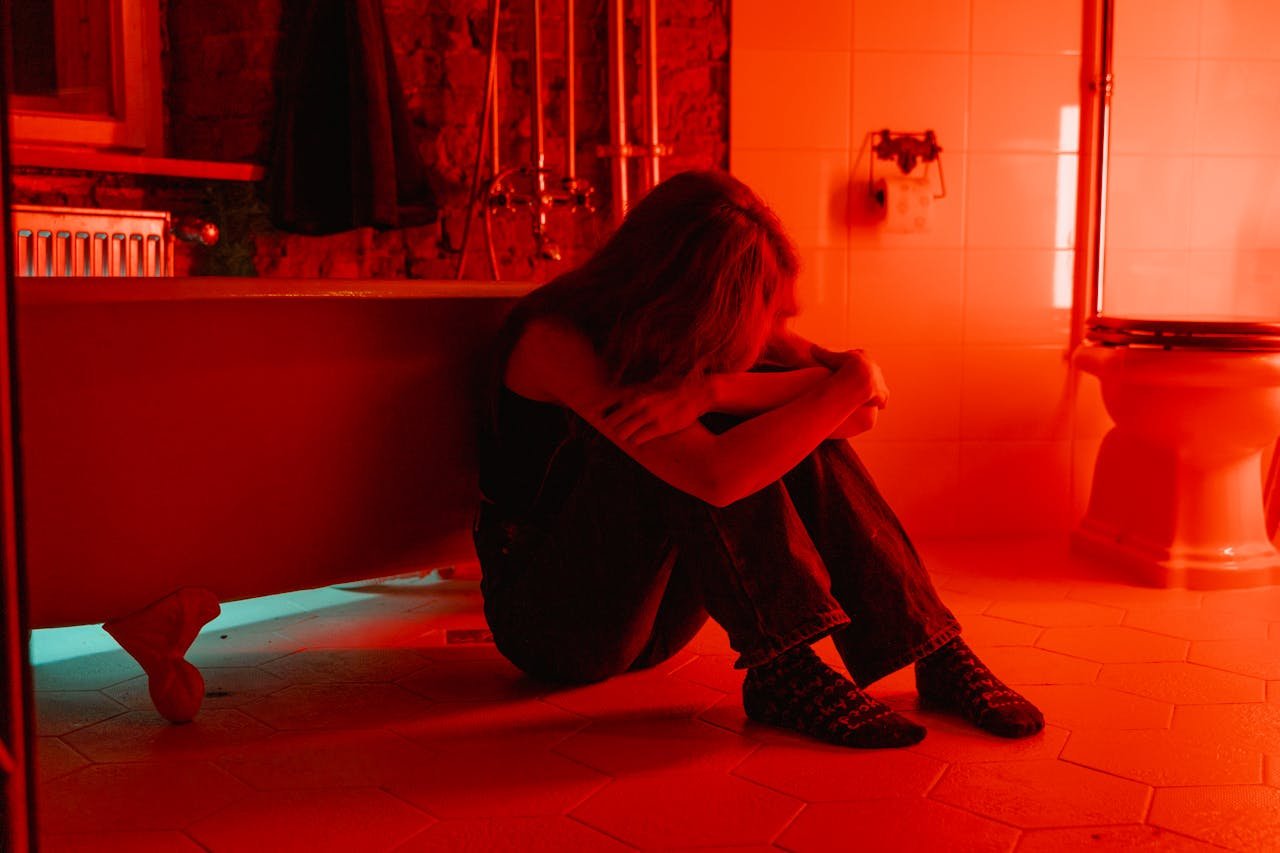 Woman sitting on the bathroom floor worrying about how to tell if someone is using cocaine.
