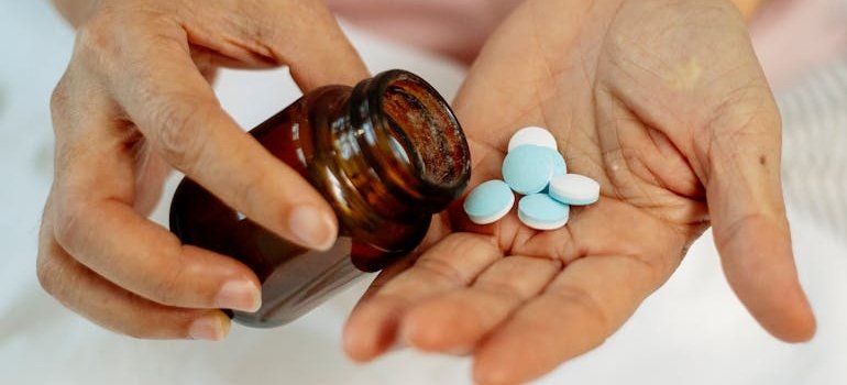 Person putting pills in the palm of their hands.