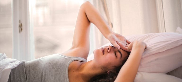 Woman lying in bed while having a headache.