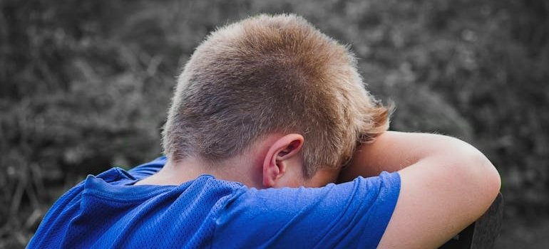 Sad younger boy covering his face.
