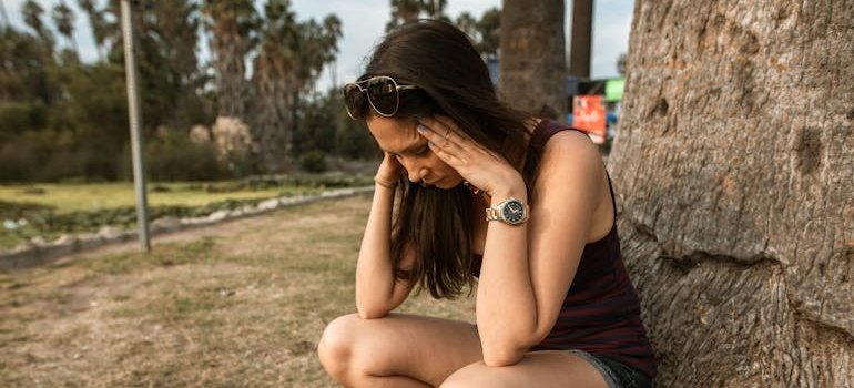 Woman crouching by the tree while having a panic attack.