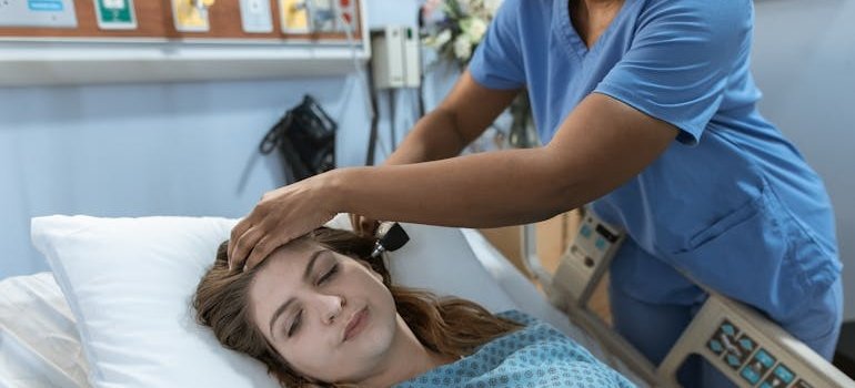 Woman lying in a hospital bed while being examined by a nurse.