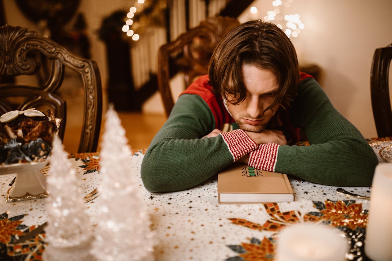 Depressed man sitting at holiday dinner and thinking about how to beat the holiday blues.