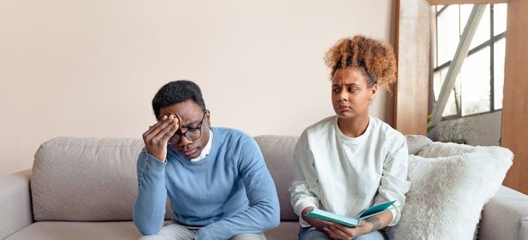 Couple sitting on the couch and having a serious conversation.