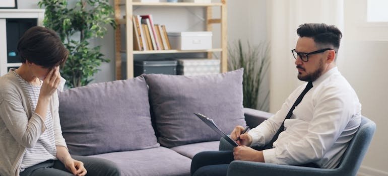 Therapist writing in a clipboard while talking with a patient about how to develop self-esteem.