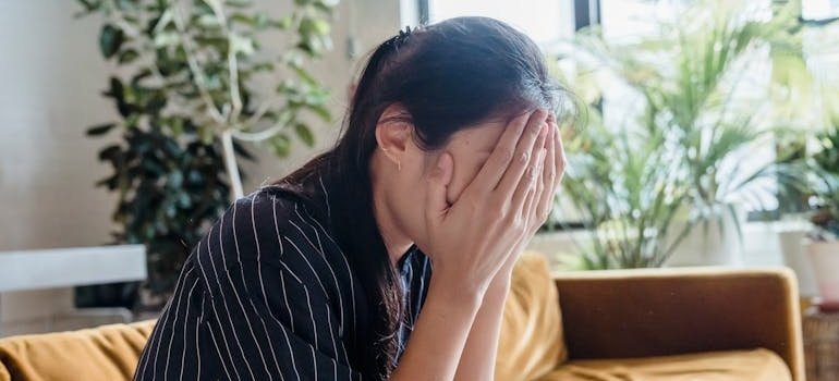 Woman covering her face with her hand while worrying about how long does weed paranoia last.