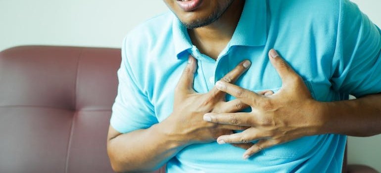 Men holding his chest in pain while suffering with a benzodiazepines overdose.