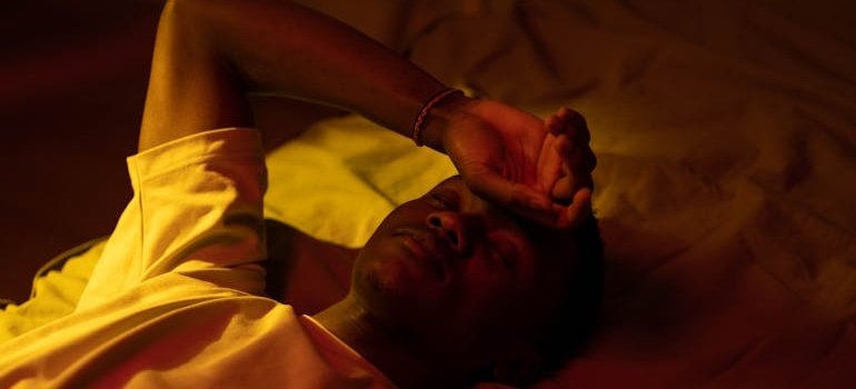 Man lying in bed and worrying about the effects of long term Adderall abuse.