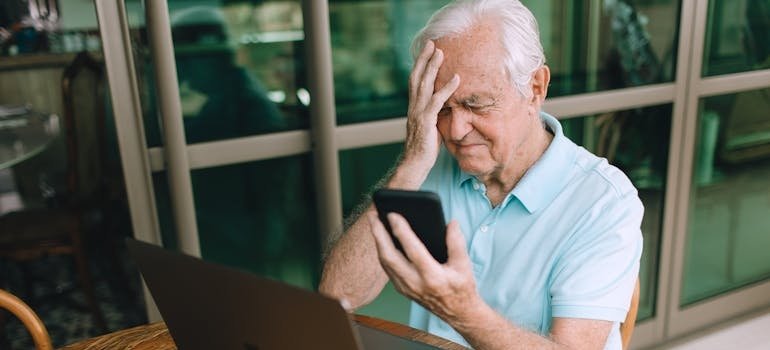 Confused elderly man looking at his phone.