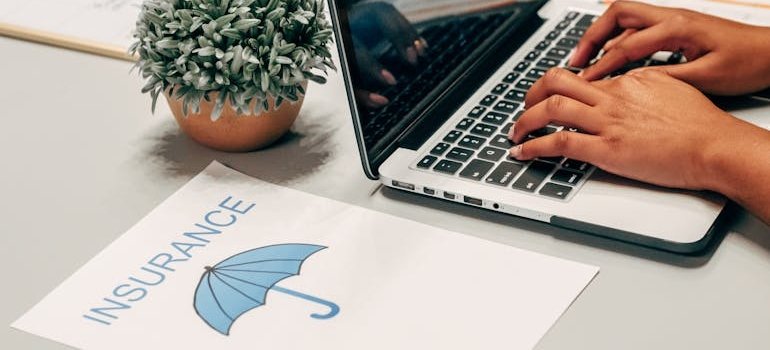 Person looking up how to transfer from one rehab facility to another on their laptop with insurance papers next to the laptop.