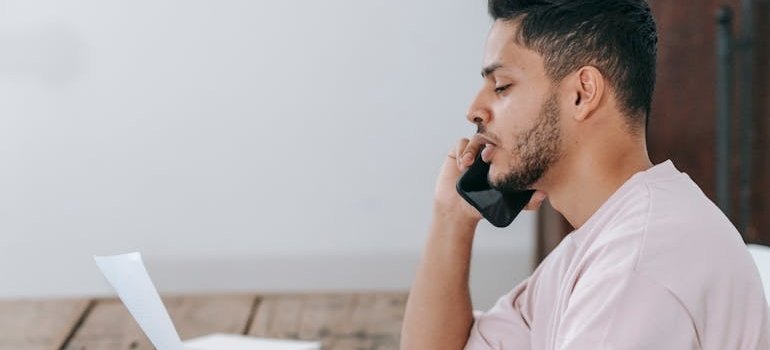 Man looking at a document while talking on the phone.