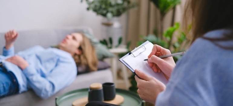 Therapist writing in a clipboard while talking to a patient about what is high intensity drinking.
