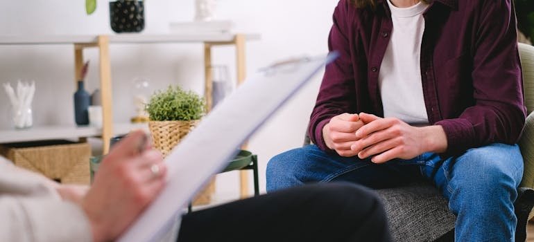 Therapist writing in a clipboard while trying to diagnose a patient with one of the common mental health disorders.
