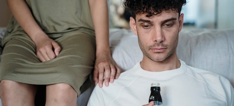 Woman sitting next to her boyfriend who is holding a bottle of alcohol.