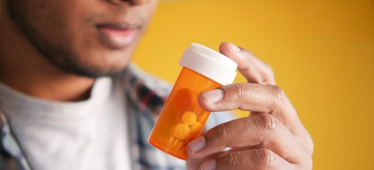 Man reading a medication label on a prescription bottle of pills.