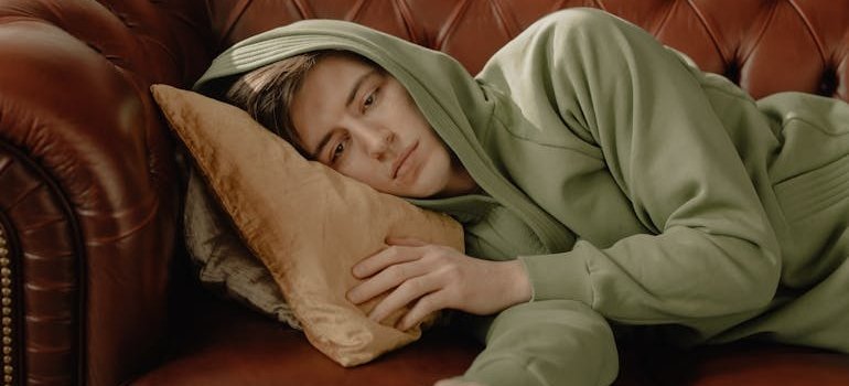 Bored man lying on the couch and watching TV.