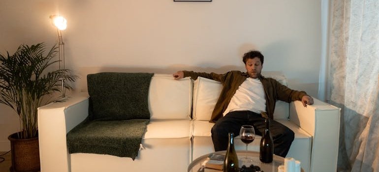 Man sitting on the couch after drinking a glass of wine.