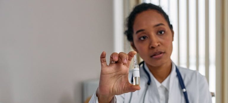 Doctor holding a glass vial filled with medication.