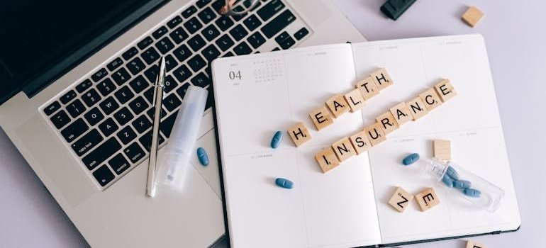 Health insurance spelled with letter blocks on top of a notebook.